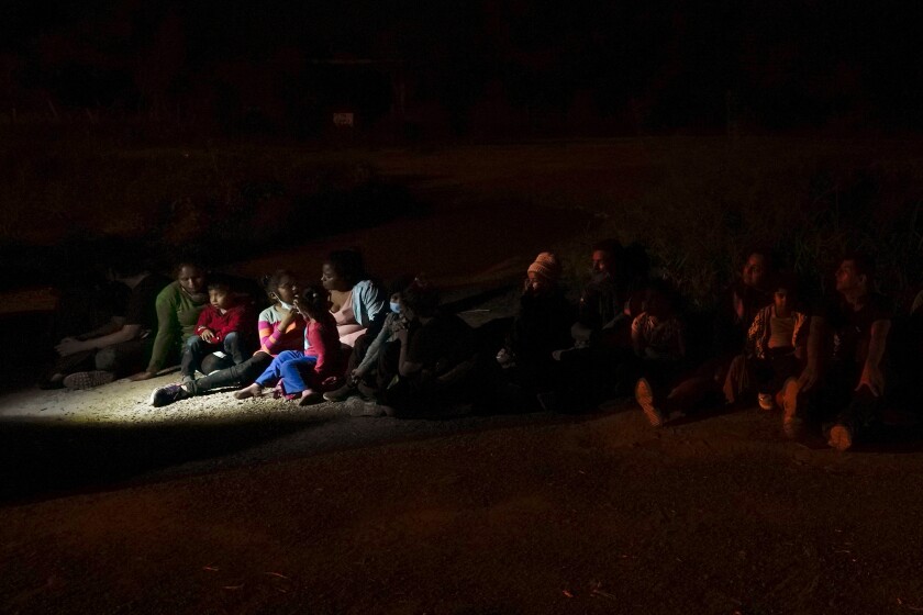 Migrants sit after turning themselves in upon crossing the U.S.-Mexico border 