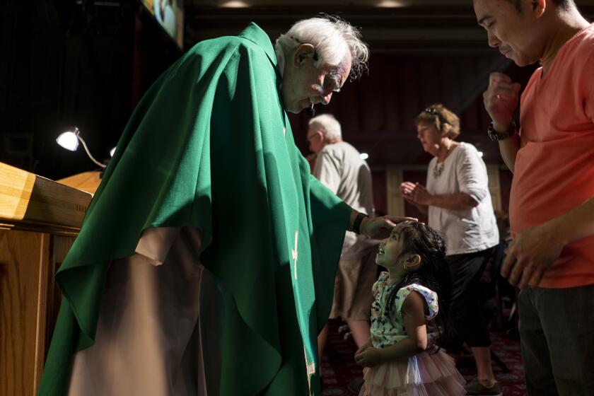 LAUGHLIN, NEV. - NOVEMBER 10: Father Charles Urnick, of St. John the Baptist Catholic Church, greets Meg Domingo and her father July Domingo, of Bullhead, during mass held in the Don's Celebrity Theater at the Don Laughlin Riverside Hotel and Casino on Sunday, Nov. 10, 2019 in Laughlin, Nev. (Kent Nishimura / Los Angeles Times)