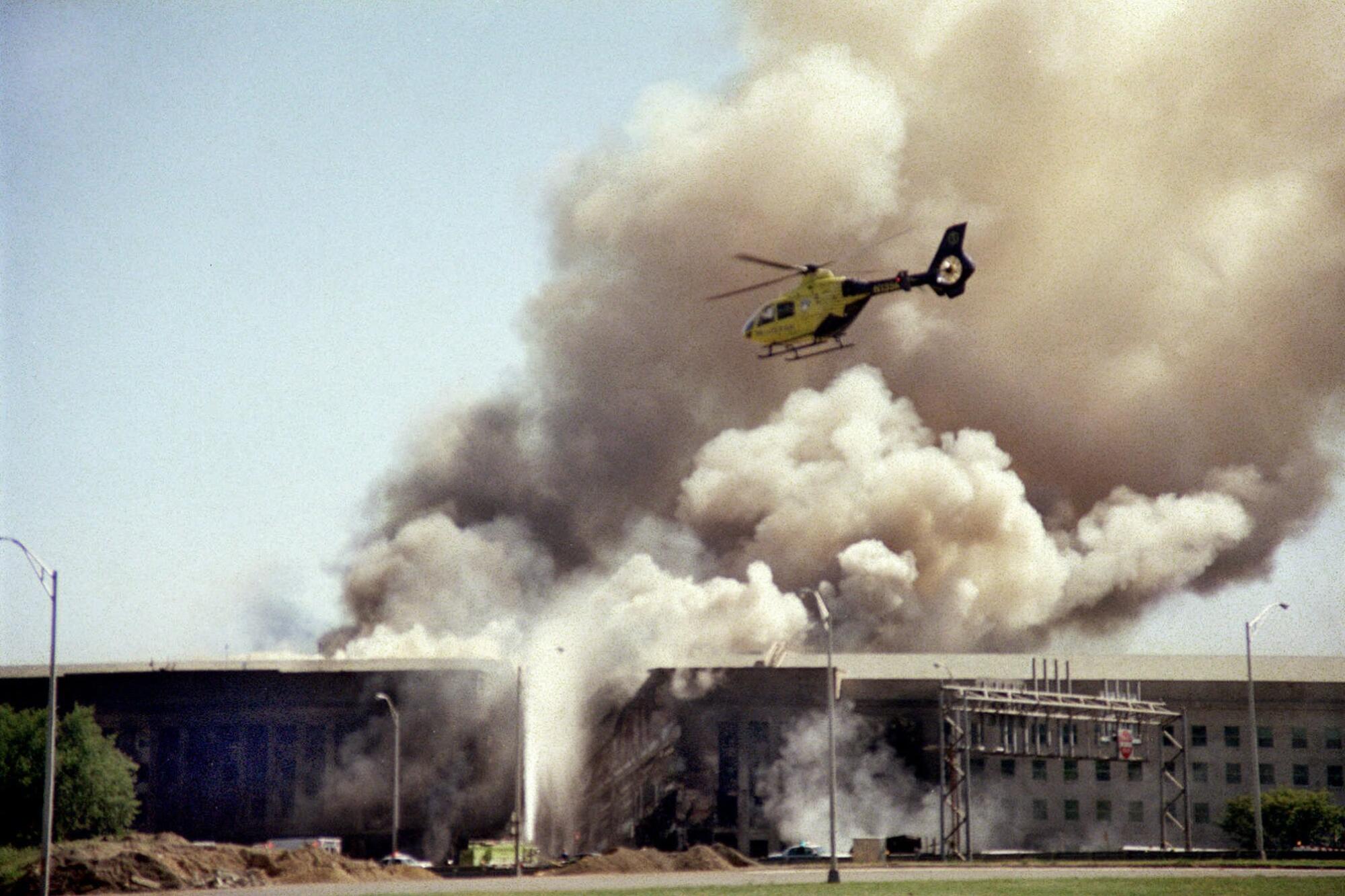 A helicopter flies over the smoking Pentagon building