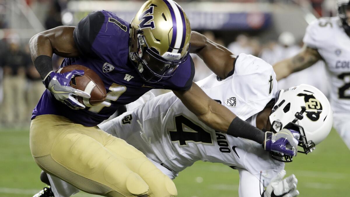 Washington wide receiver John Ross (1) sends Colorado defensive back Chidobe Awuzie (4) reeling with a stiff-arm during the first half of the Pac-12 title game Friday night.