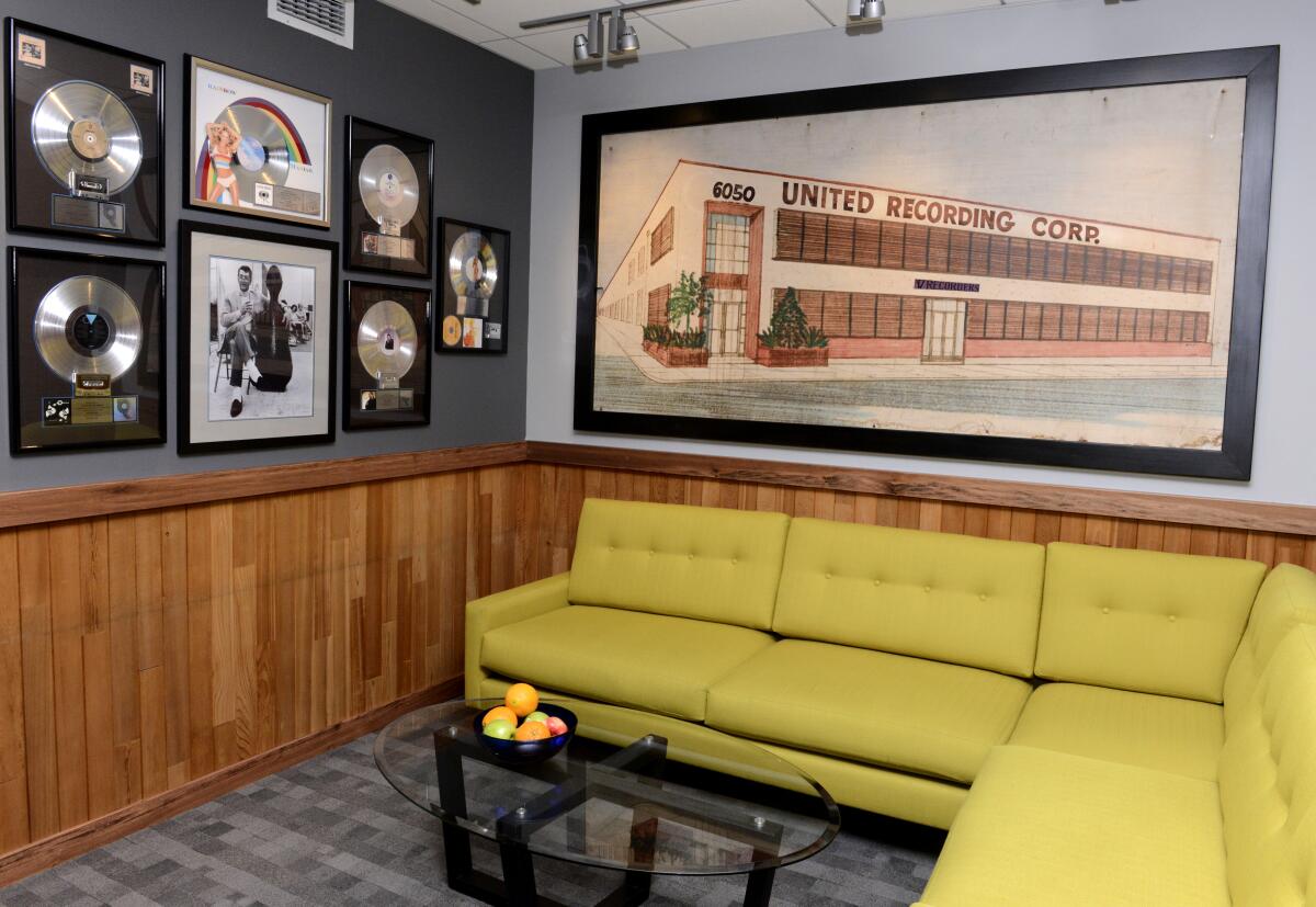 A recording studio lobby with a framed albums and a large picture of a building on the walls.