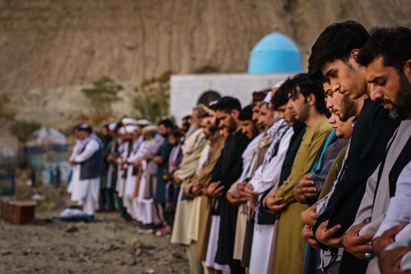 KABUL, AFGHANISTAN -- AUGUST 30, 2021: Islamic prayers are recited for the dead before they could be laid into the ground to be buried, as around 200 people attend a mass funeral for the 10 people the family said to have been killed in a U.S. drone strike, in Kabul, Afghanistan, Monday, Aug. 30, 2021. (MARCUS YAM / LOS ANGELES TIMES)