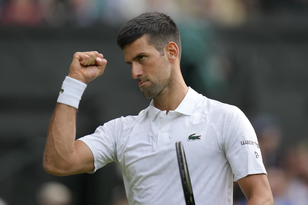 Novak Djokovic raising a fist after winning a set at Wimbledon.