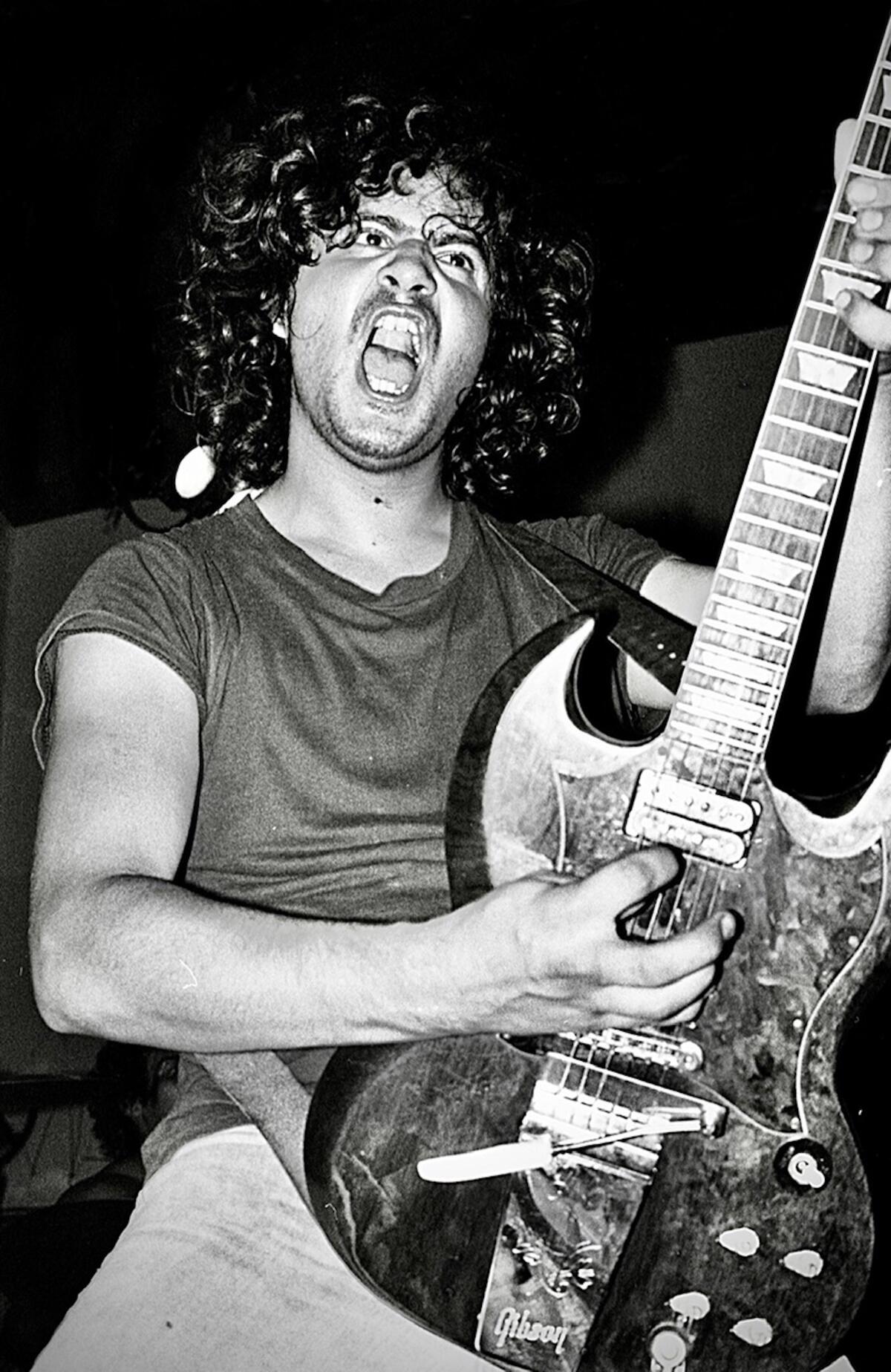 A man playing the electric guitar and snarling
