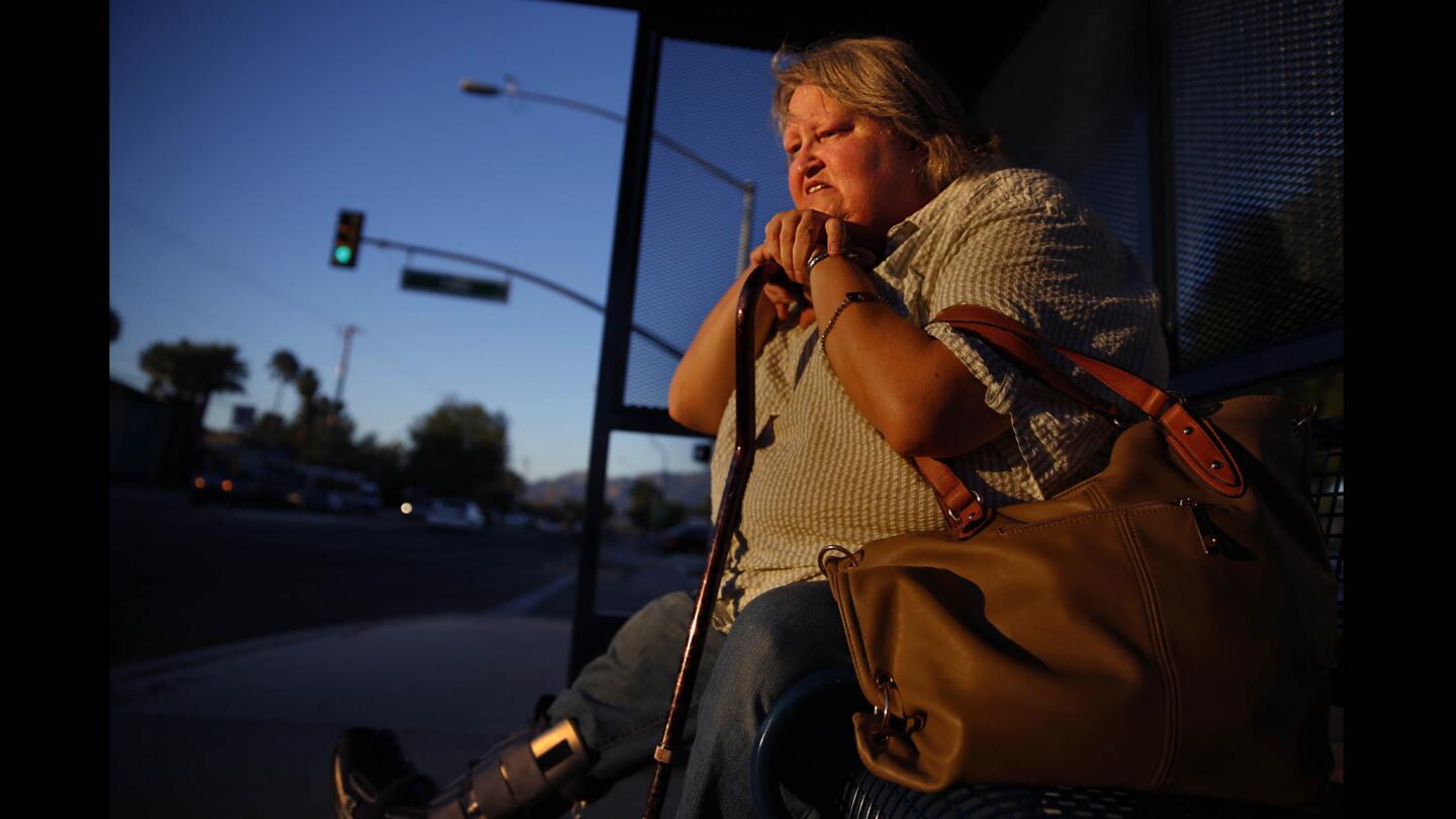Karen Slone waits on a Tucson bus bench near her Tucson home. A special boot protects her foot after she lost part of it to an infection related to her diabetes. She delayed treatment because she had no health coverage, she said. Many Arizonans lost coverage during the recession when the state cut Medicaid access.