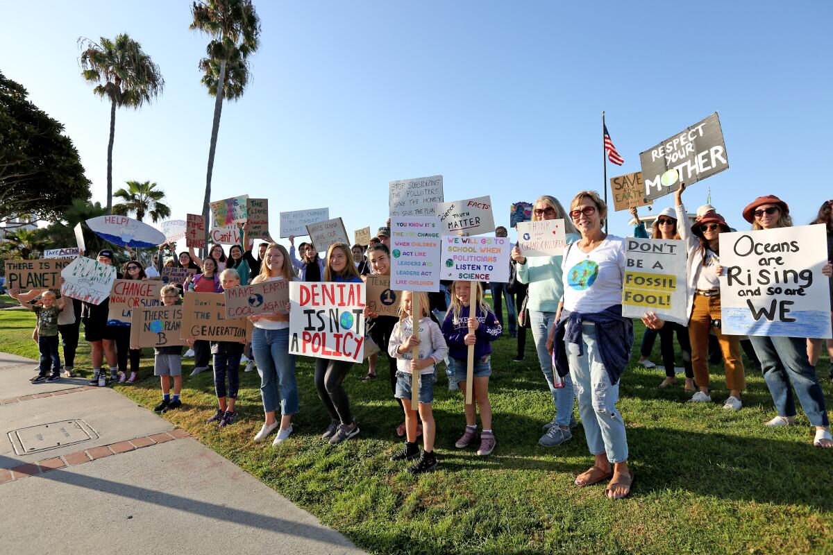People hold protests sign during the Climate Strike climate change protest in Laguna Beach.