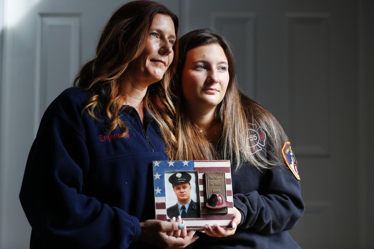 Pamela Yarosz and her daughter hold a photo of New York firefighter Christopher Michael Mozzillo.