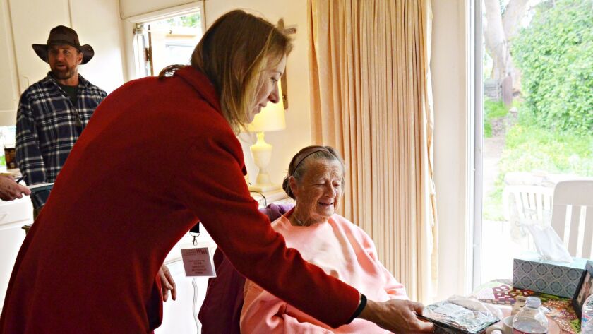 Encinitas Mayor Catherine Blakespear, left, delivers a hot lunch with Meals on Wheels to 87-year-old Kathy Brown.