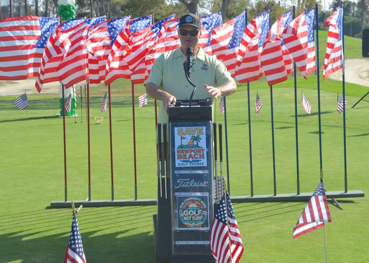 Tim Sullivan of Newport Harbor American Legion Post 29, stands at a podium on July 3, 2025. American flags fly behind him.