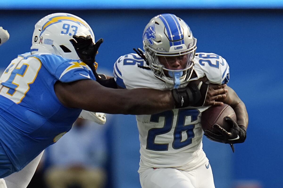 Detroit Lions running back Jahmyr Gibbs, right, is tackled by Chargers defensive tackle Otito Ogbonnia.