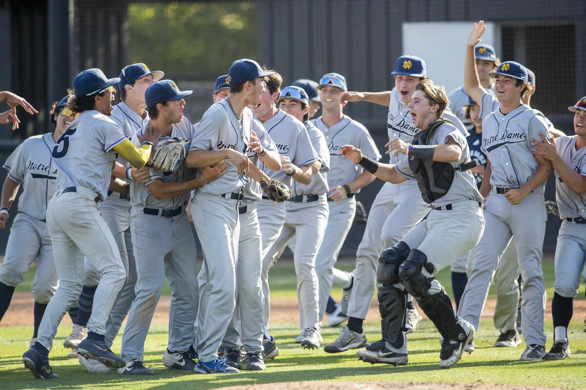 Sherman Oaks Notre Dame's players mob pitcher Oliver Boone after the Knights beat Huntington Beach 2-0 on Tuesday.
