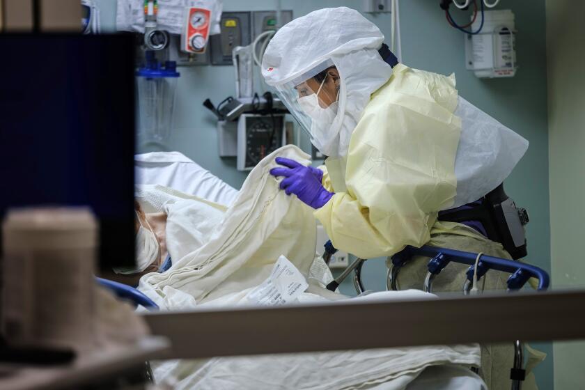 SAN DIEGO, CALIF. -- FRIDAY, APRIL 10, 2020: Wearing personal protective equipment, RN April Bandi, cares for a patient under investigation that have possible COVID-19 symptoms, inside a special negative pressure isolation room at the Emergency Department, at Sharp Memorial Hospital in San Diego, Calif., on April 10, 2020. (Marcus Yam / Los Angeles Times)