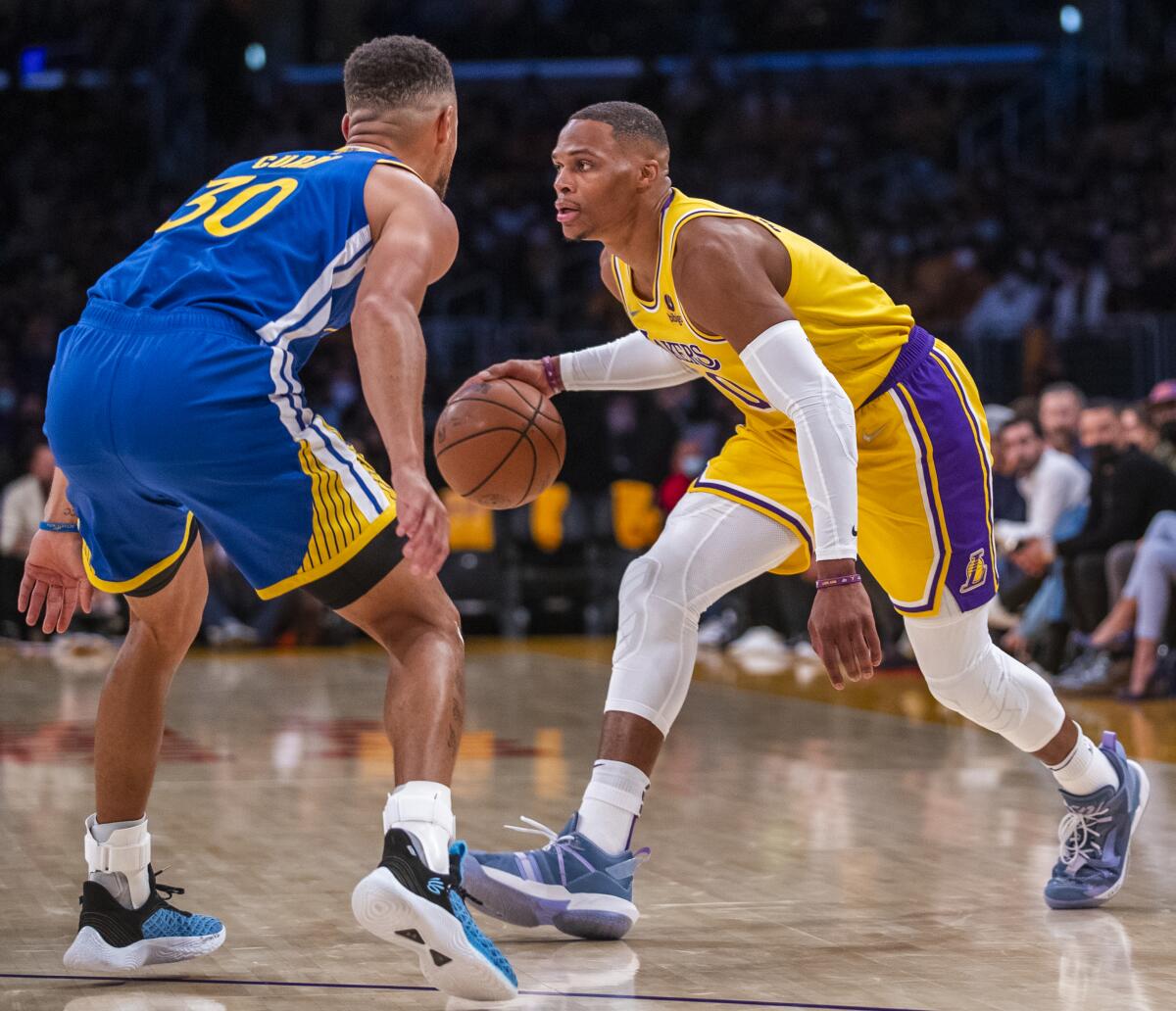 Lakers guard Russell Westbrook controls the ball in front of Warriors guard Stephen Curry.