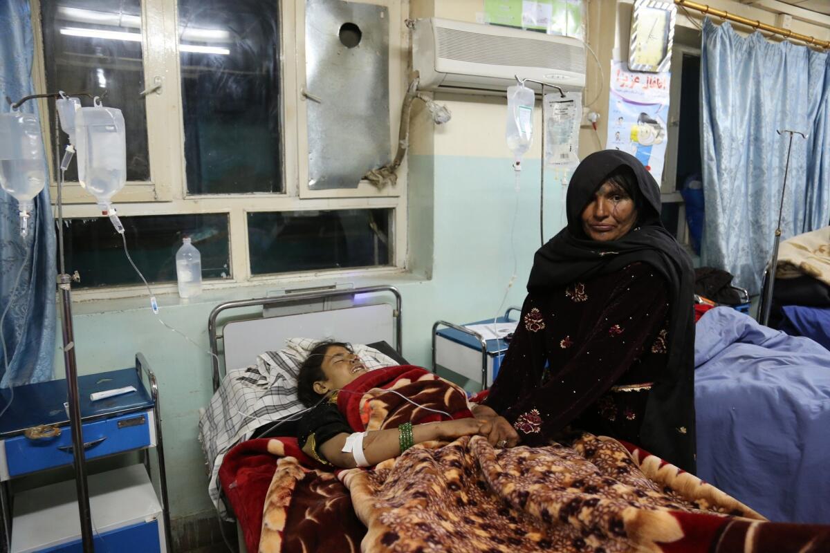 A woman holds the hands of a roadside-bomb victim at a hospital in the Andar district of Afghanistan's Ghazni province.