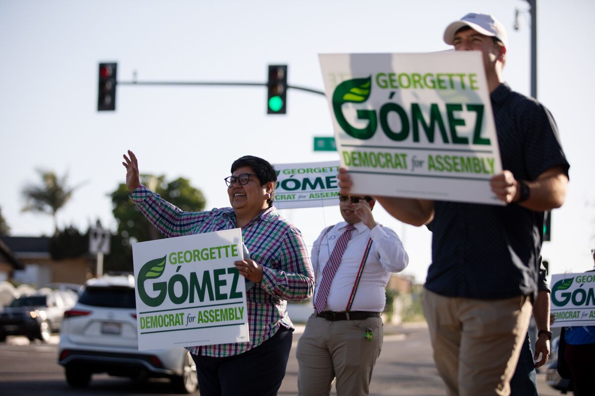 Candidate Georgette Gómez holds a sign and waves to passing motorists on the corner of Telegraph Canyon Road 