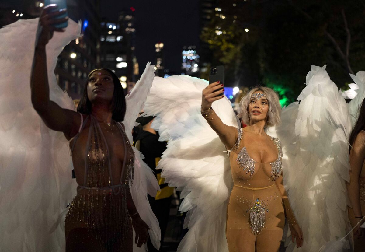 Costumed Halloween revelers take pictures with their phones before the start of New York City's 48th annual Greenwich Village Halloween Parade, Sunday, Oct. 31, 2021, in New York. (AP Photo/Dieu-Nalio Chery)