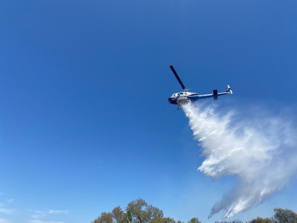 A helicopter makes a water drop Wednesday on a fire off Riverview Parkway in Santee.
