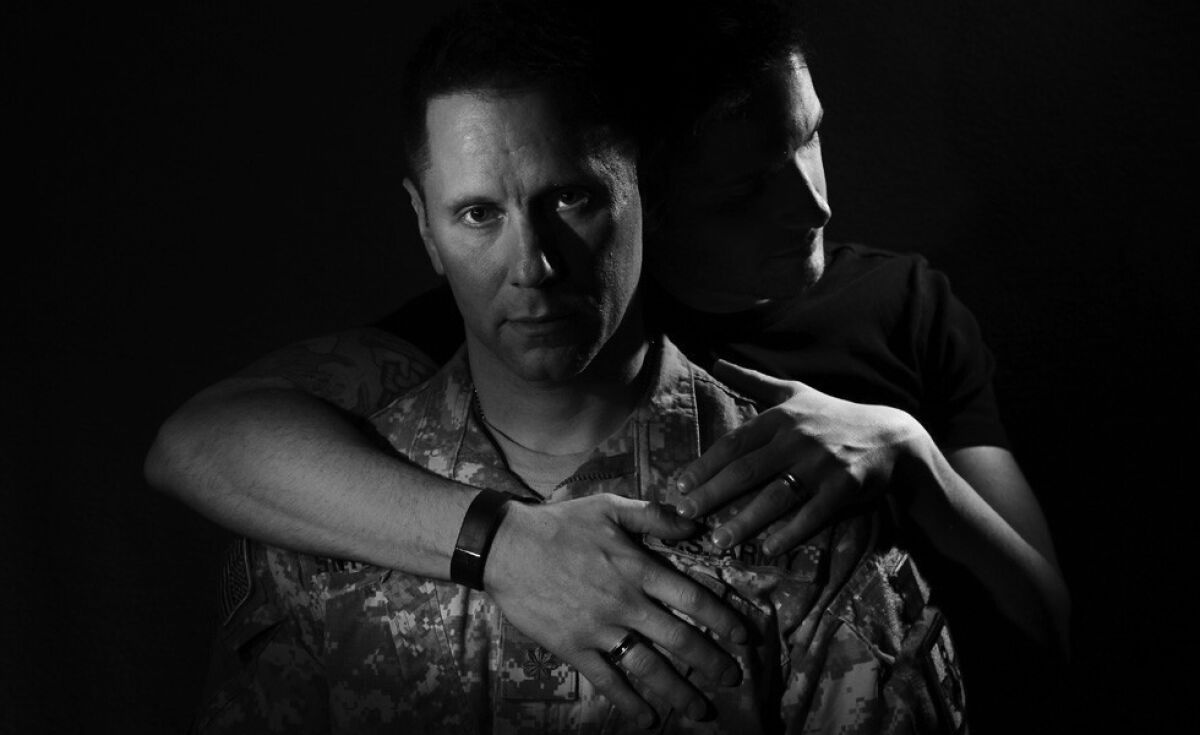Stephen Snyder-Hill, 43, an Army reservist who has served two tours in Iraq, is held by his husband Josh Snyder-Hill, 34, inside their Columbus, Ohio home. Stephen Snyder-Hill hid is sexuality for more than 20-years from the military and endured an often anti-gay climate while maintaining his secret. While serving his second tour of Iraq, Stephen Snyder-Hill submitted a question for the Republican presidential debate via YouTube that asked if any of the candidates would seek to reinstate the military's "Don't Ask, Don't Tell" policy regarding gays serving in the military. Some in the audience booed Snyder-Hill and his face became an icon for gays in the military. The couple have used the exposure to highlight their situation. The two were married in May of 2011 while Stephen was on leave from his tour of Iraq. ( Rick Loomis / Los Angeles Times )