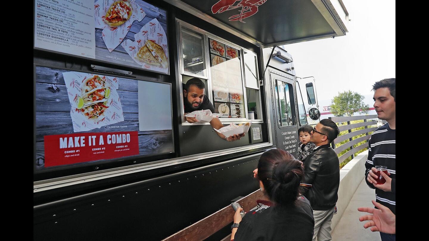 Co-owner Yatrik Bhatt hands a customer her order from the new Orange County food truck, Cousins Maine Lobster parked at Bruery Terreux Tasting Room in Anaheim on Friday, March 29, 2019