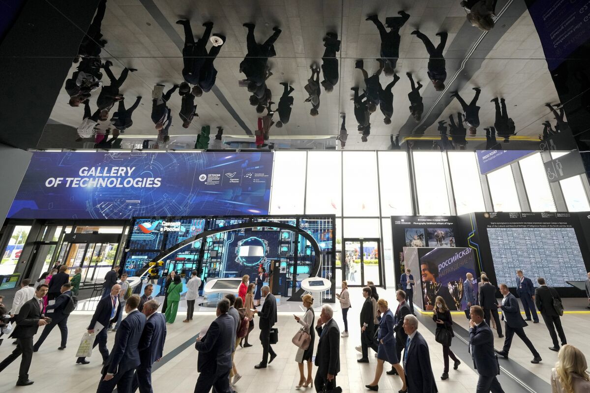 Participants are reflected in the ceiling as they enter a hall at the St. Petersburg International Economic Forum in St.Petersburg, Russia, Wednesday, June 15, 2022. Russia’s annual event to tout its investment opportunities this year was shadowed by the stern international sanctions imposed on the country after the Kremlin sent troops into Ukraine four months earlier and by the extensive disapproval of foreign businesses, which have suspended operations or pulled out entirely, leaving Russian shopping centers pocked with dark, shuttered stores. (AP Photo/Dmitri Lovetsky)