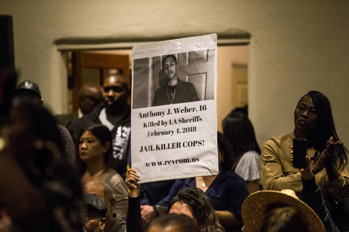 A sign with a photo of slain 16-year-old Anthony Weber is held up during an emergency town hall meeting.