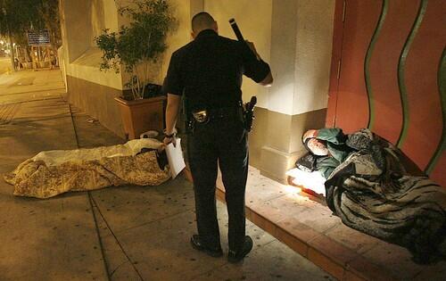 Senior Lead Officer Mike Fernandez checks a man sleeping on Main Street at Our Lady Queen of Angels Church in Los Angeles early Tuesday. The L.A. Police Department counts downtowns homeless population every two weeks to measure the problem.