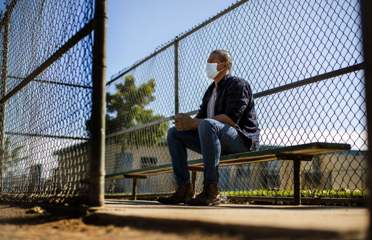 Evie Junior sits on a bench at a baseball diamond near his home in Anaheim