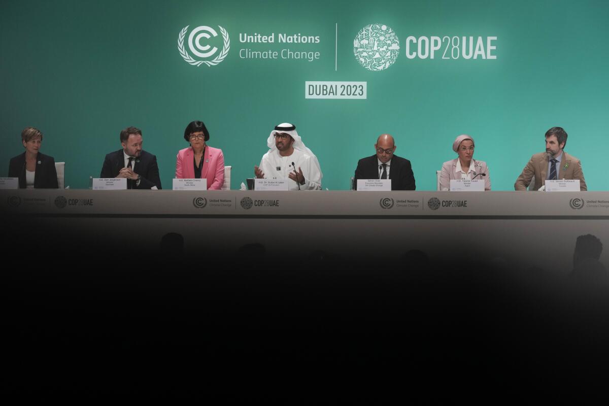 A man sits among a group of seven people under the COP28UAE logo.