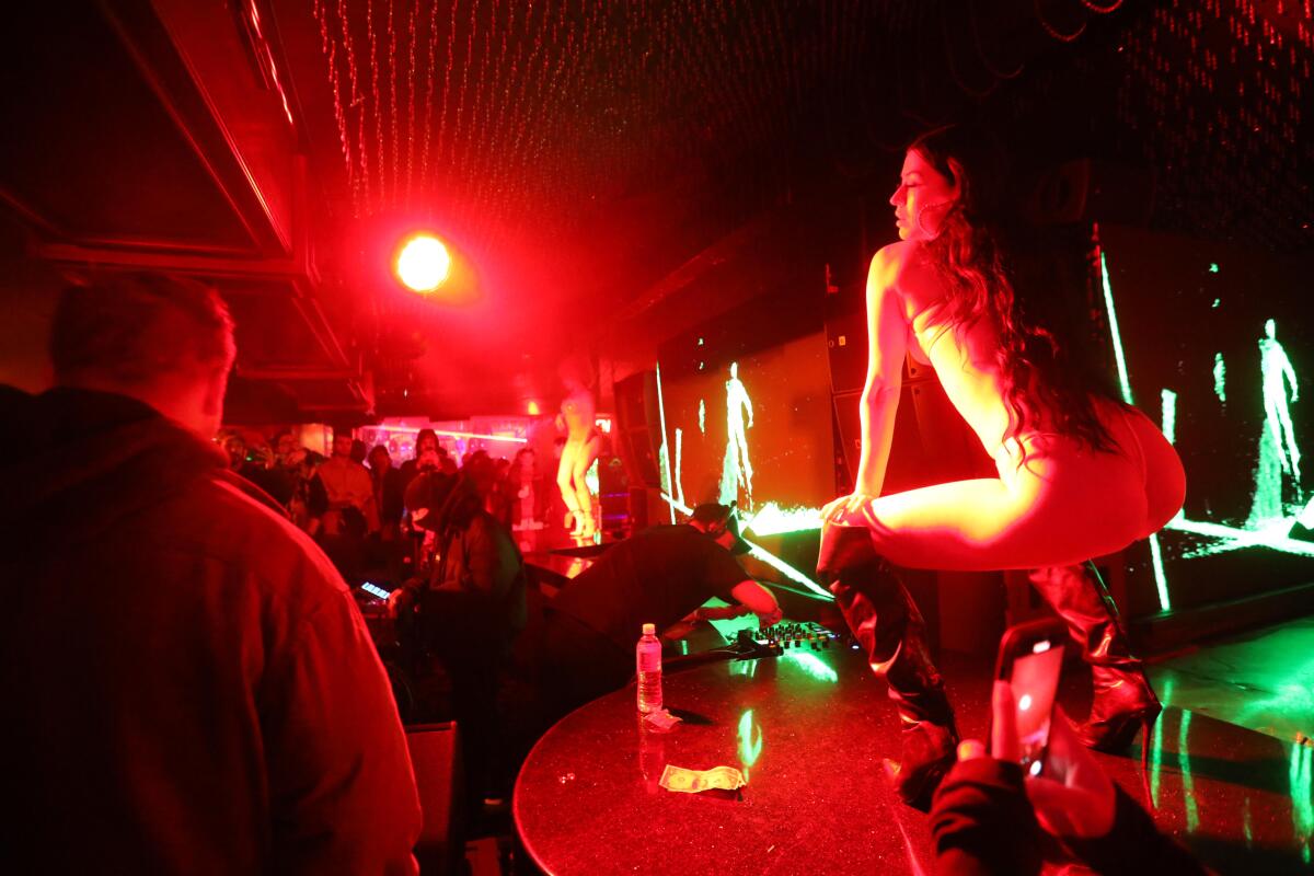 A stripper dances as DJ AraabMuzik plays after the Los Angeles premiere of director Harmony Korine's film. "Aggro Dr1ft"
