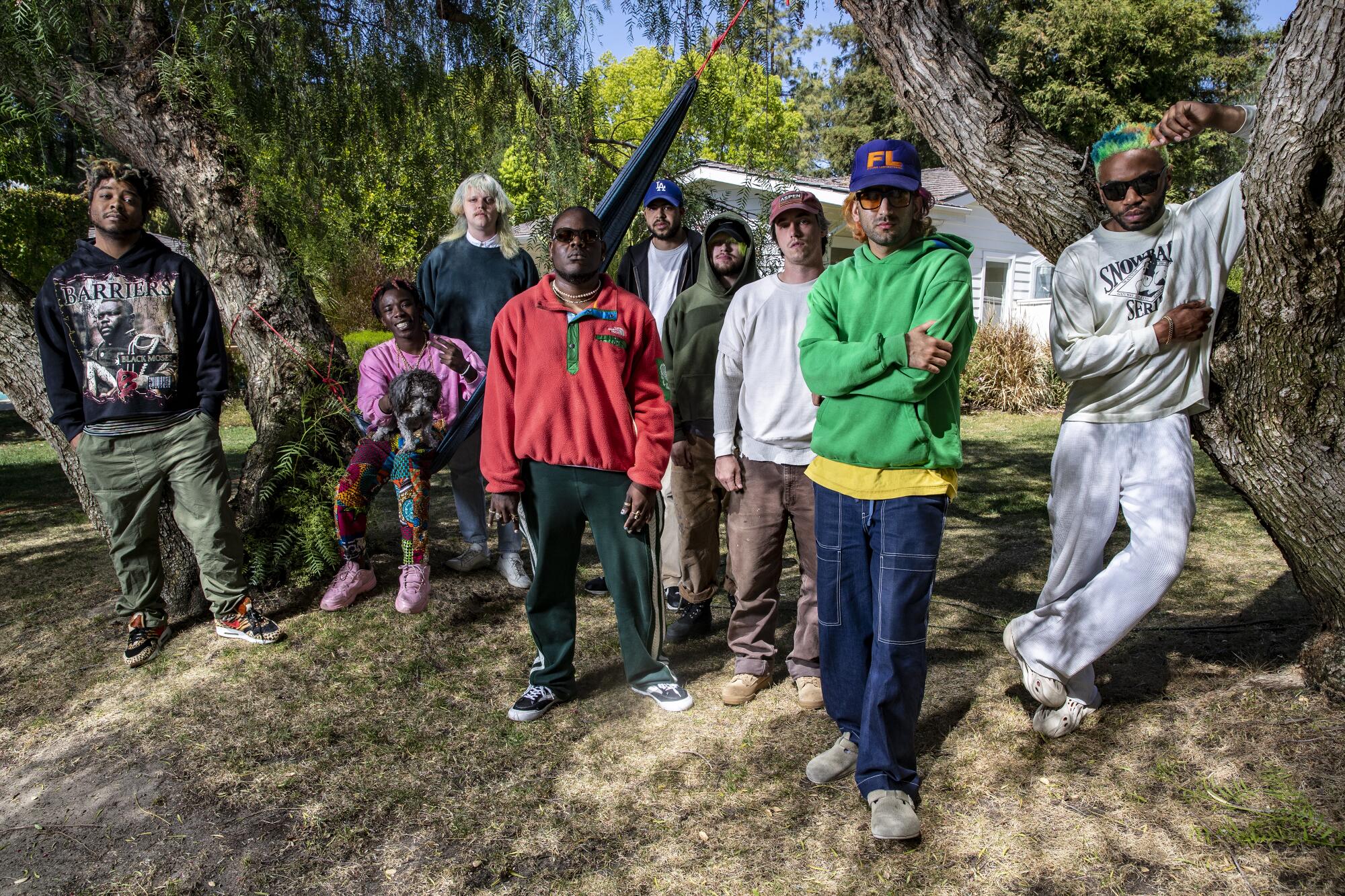 The members of Brockhampton gather under trees.