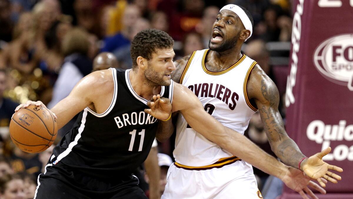Cavaliers forward LeBron James tries to hold his defensive position as Nets center Brook Lopez (11) works in the post during the second half Saturday.