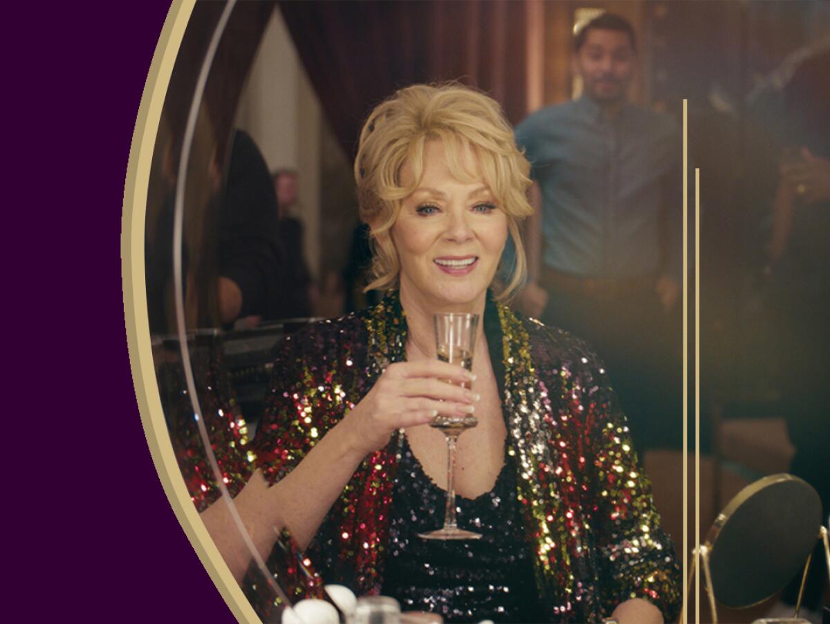 Jean Smart sits in front of a mirror holding a glass.