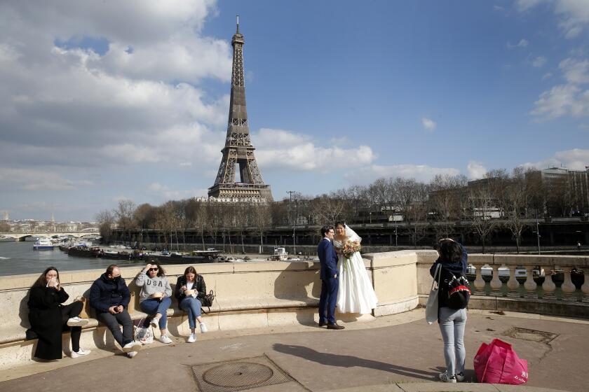 A newly married couple poses in front of the Eiffel Tower during the Coronavirus pandemic on February 26, 2021 in Paris, France.