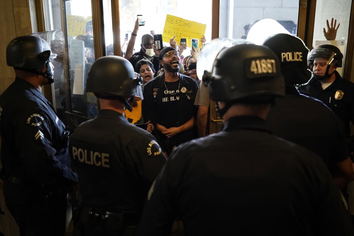 Un grupo de manifestantes corea lemas mientras confronta a la policía a la entrada del ayuntamiento de Los Ángeles 