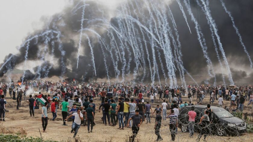 Palestinian protesters flee from incoming teargas canisters during clashes with Israeli forces along the border with the Gaza Strip east of Gaza City on May 4, 2018.
