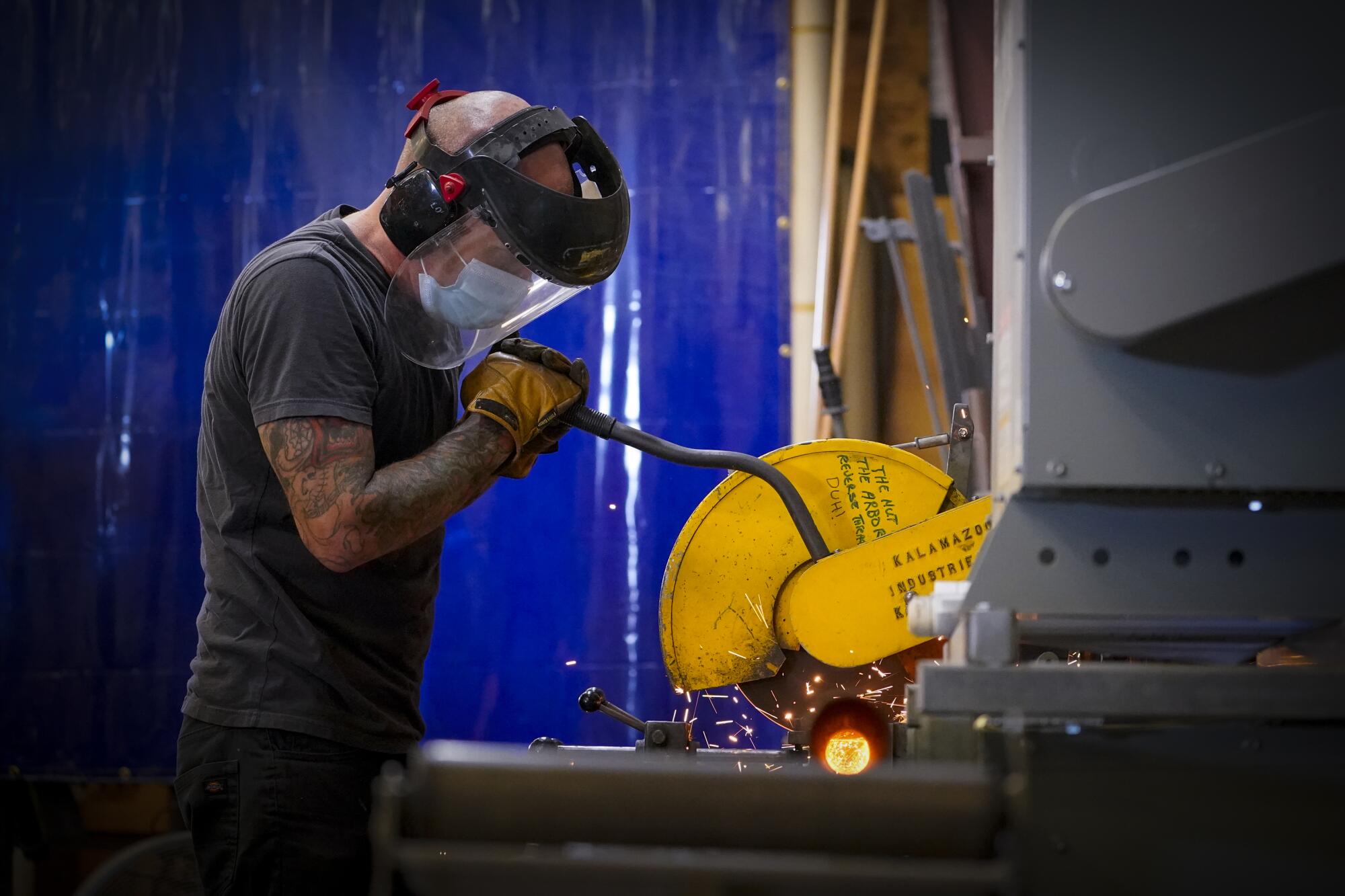 Jason Crutchfield uses a metal cutting saw to cut several pieces of pipes to be used in the fabrication of props.