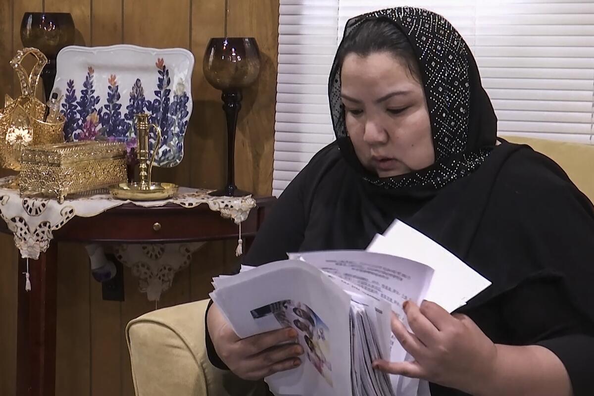 FILE - In this image from video, Zumret Dawut, a Uighur from China's western Xinjiang region who forcibly sterilized for having a third child after being released from a Xinjiang detention camp, looks at documents at her home in Woodbridge, Va., on Monday, June 15, 2020. For Dawut and other camp survivors who spoke out, the U.N.'s report on the mass detentions and other rights abuses against Uyghurs and other mostly Muslim ethnic groups in Xinjiang was the culmination of years of advocacy, and a much-welcome acknowledgement of the abuses they say they faced at the hands of the Chinese state. (AP Photo/Nathan Ellgren, File)