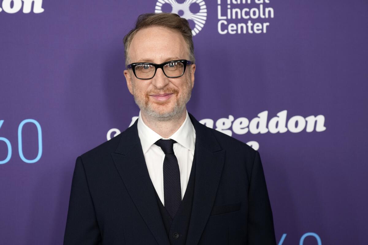 A man in glasses wearing a black suit and tie.