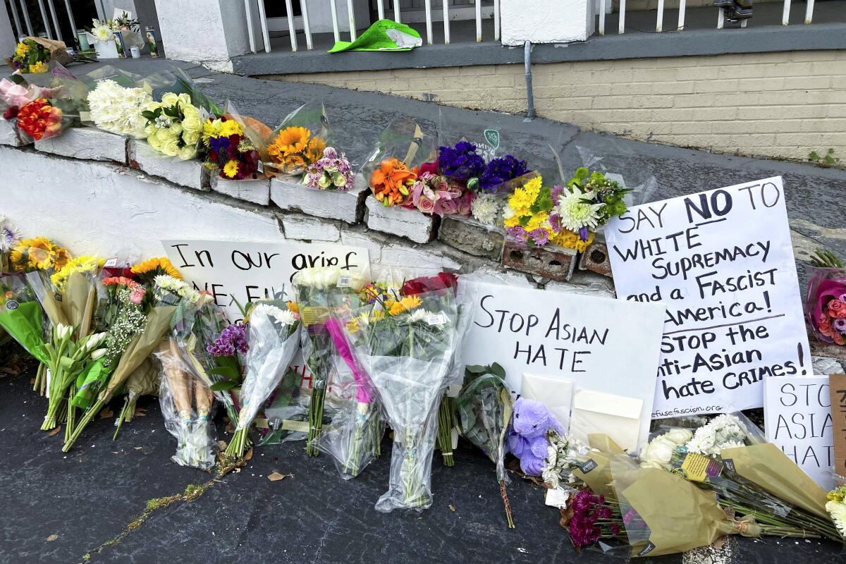 Flowers and candles sit alongside signs, one of which says "Stop Asian hate."