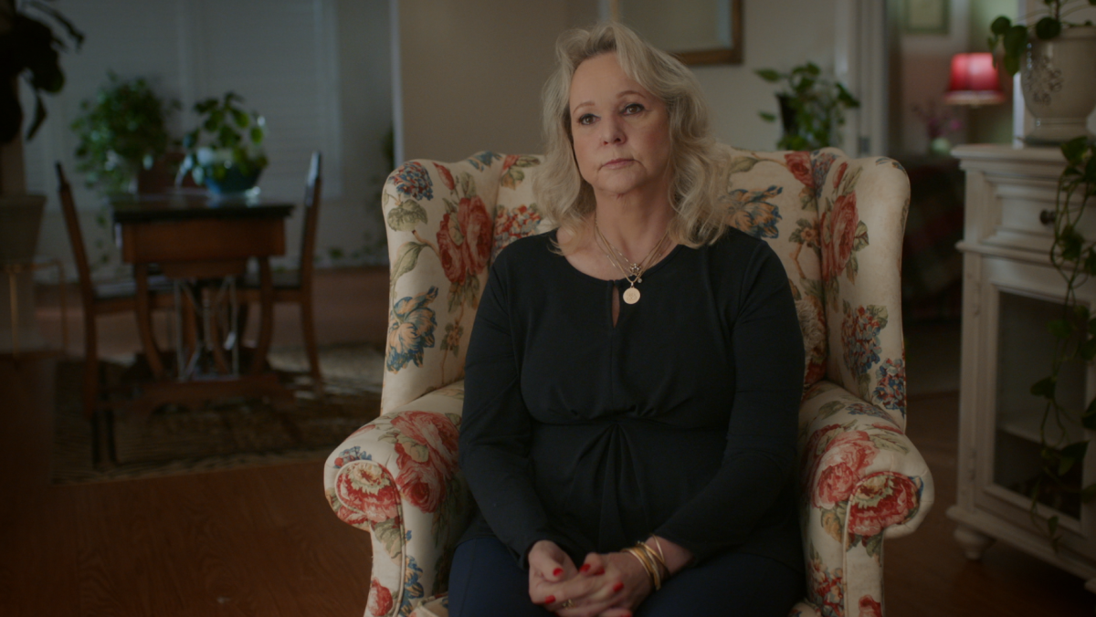 A woman sits for a television interview in a floral chair