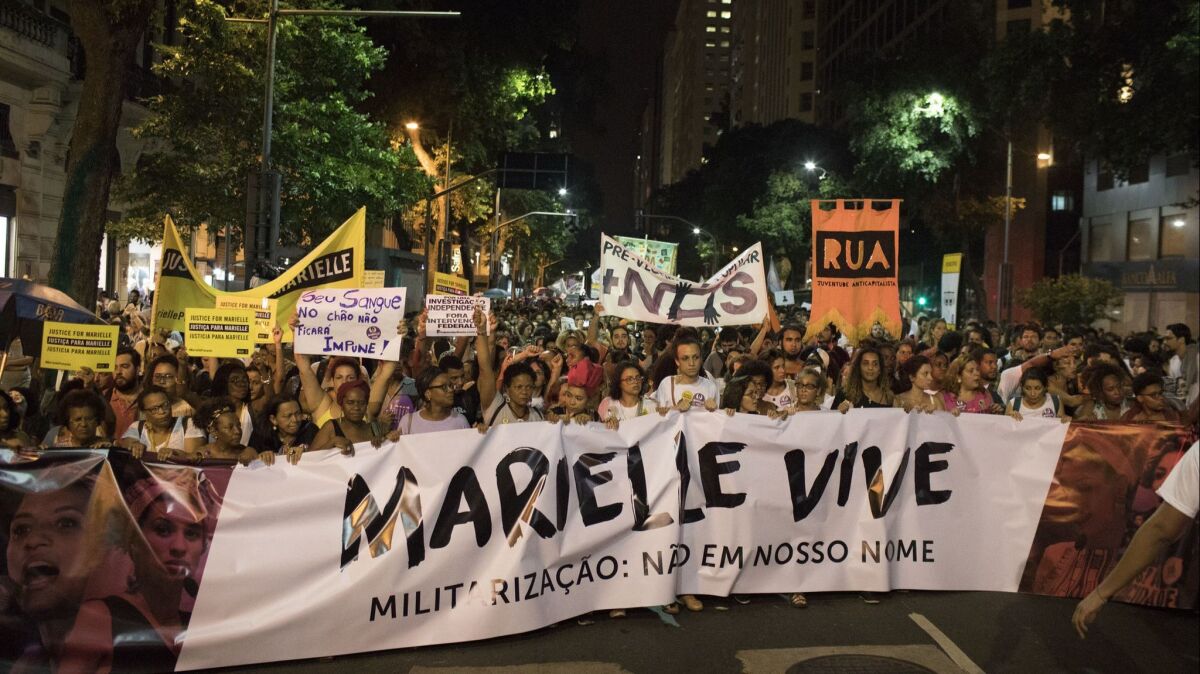 People hold a banner reading "Marielle lives" during a protest against the slaying of Councilwoman Marielle Franco.