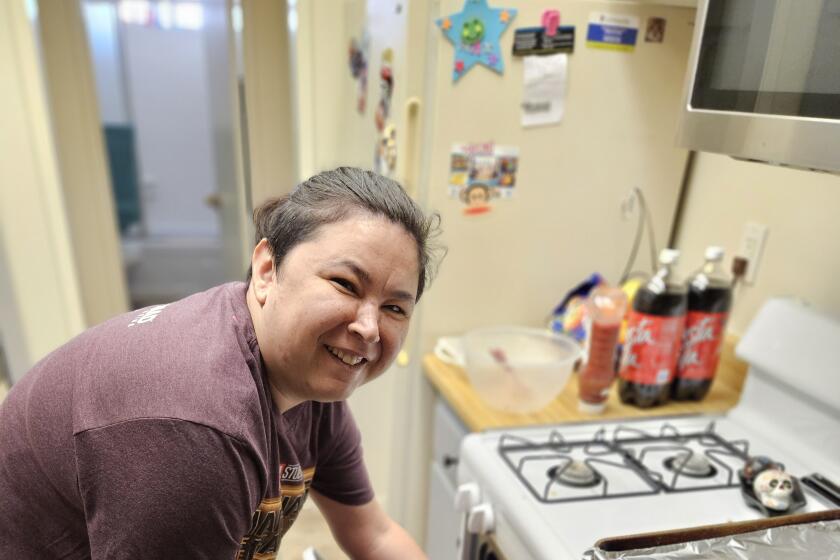 One of Home of Guiding Hands’ Independent Living Skills clients, Cassie, cooking with her staff