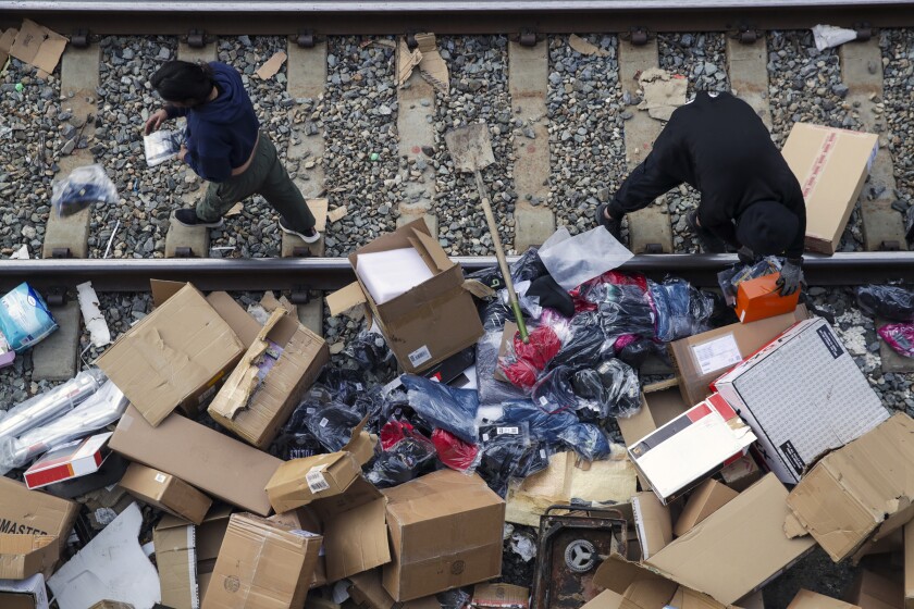 People are rummaging through boxes on the train tracks.