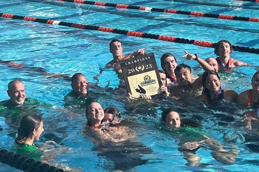 Members of the Costa Mesa High swim team celebrate after the Mustang boys won the CIF Southern Section Division 3 title on Saturday.