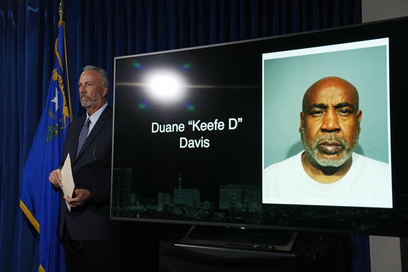 CAPTION CORRECTION: CORRECTS SPELLING OF NAME: Clark County District Attorney Steve Wolfson stands beside a photo of Duane "Keffe D" Davis during a news conference on an indictment in the 1996 murder of rapper Tupac Shakur, Friday, Sept. 29, 2023, in Las Vegas. Monitor is rear has name misspelled. (AP Photo/John Locher)