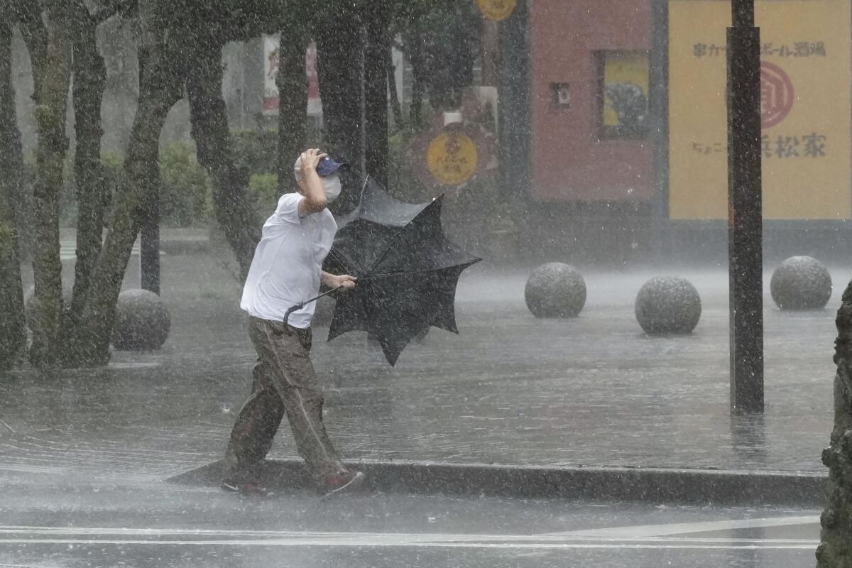 A man is drenched by the rain brought by Tropical Storm Meari, in Hamamatsu, Shizuoka prefecture, central Japan Saturday, Aug. 13, 2022. The storm unleashed heavy rains on Japan's main Honshu island as it headed northward Saturday toward the capital, Tokyo, according to Japanese weather officials. (Kyodo News via AP)