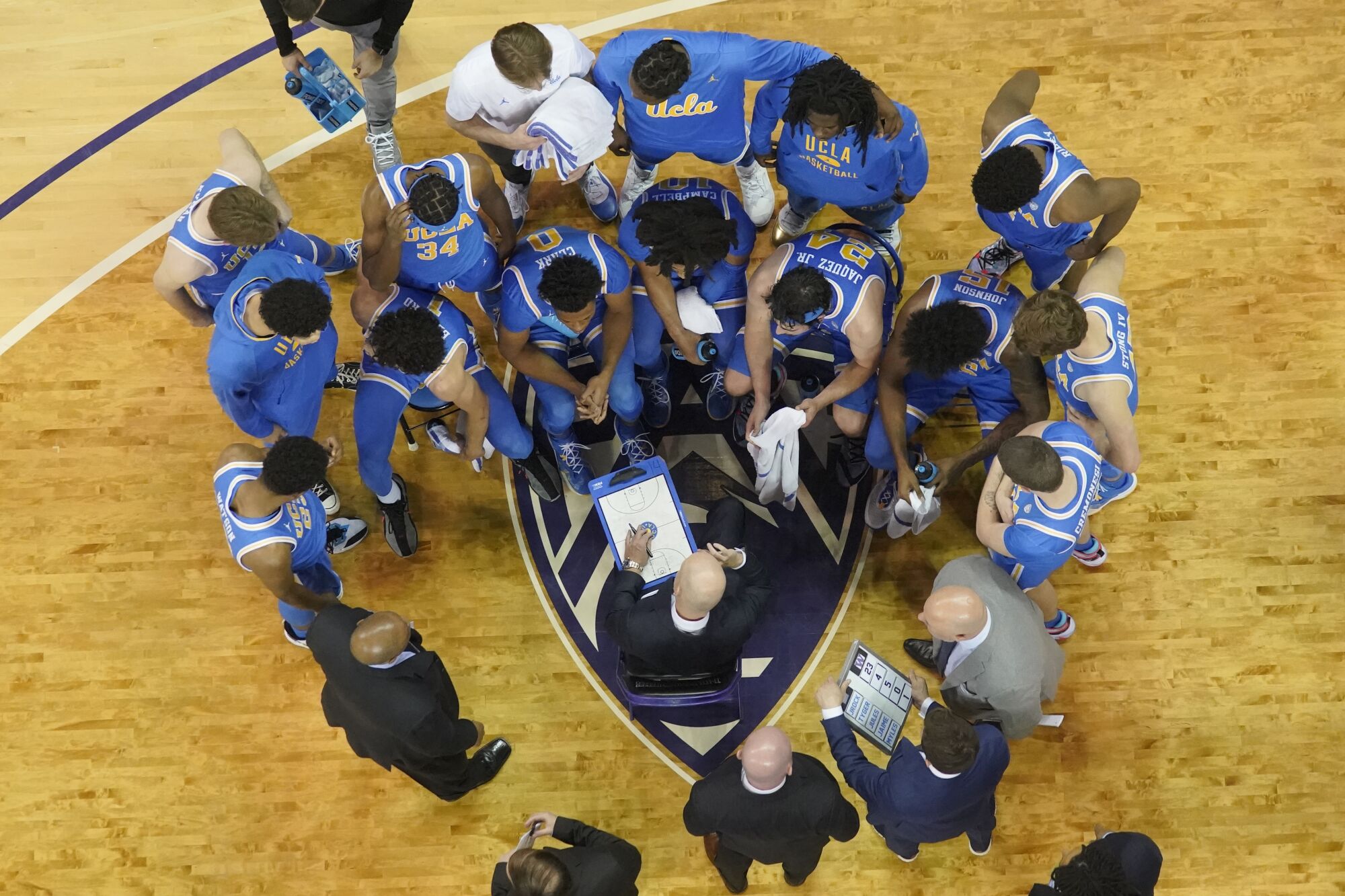 UCLA coach Mick Cronin, center, talks to his team during a time out