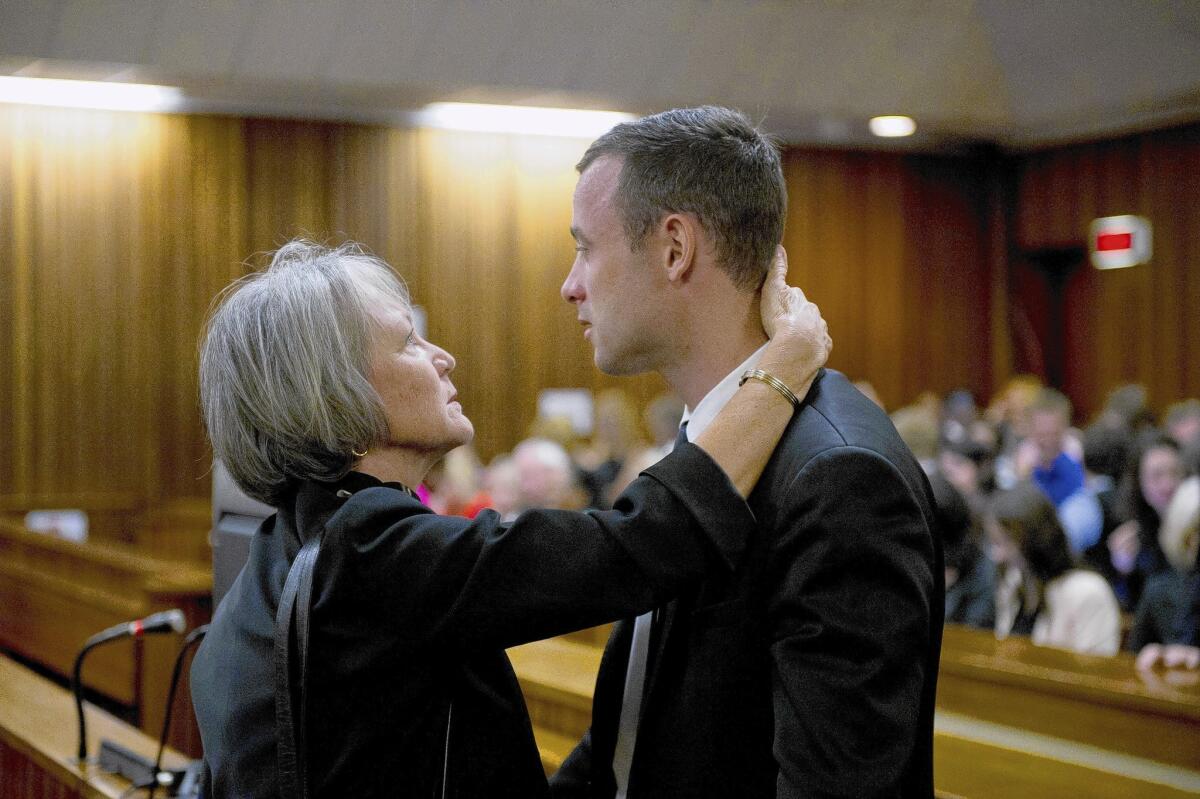 South African Olympian Oscar Pistorius speaks with a family member during his trial in Pretoria, South Africa. He has pleaded not guilty to murder in the death of his girlfriend, Reeva Steenkamp. He has said he mistook her for an intruder before shooting through a door in his apartment.