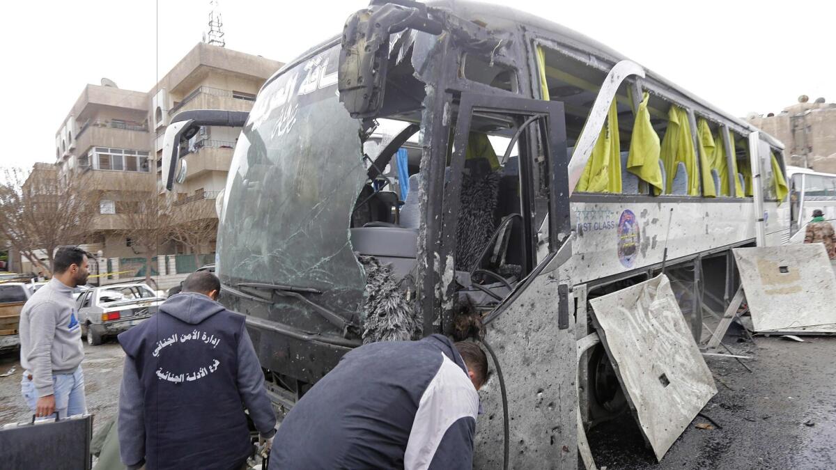 A forensics team examines a damaged bus at the scene of a bombing in Damascus' Old City on March 11, 2017.
