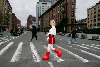 A woman wearing big red boots crosses the street